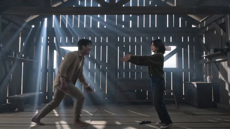 Side-on: he lunges toward her as she opens her arms, gun on the floor